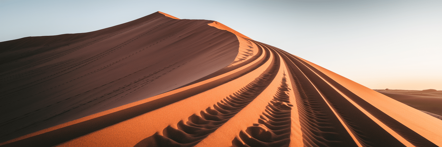 Your Essential Guide to Dubai Desert Safari Adventures 1 4x4 vehicle tracks over a red sand dune.