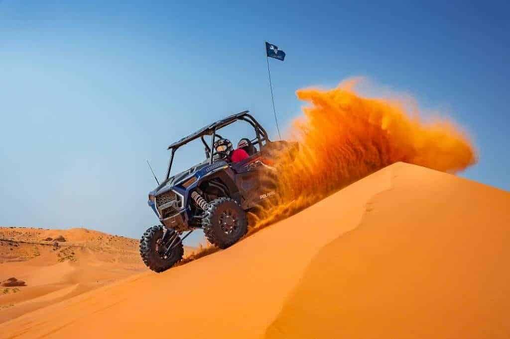 Powerful Polaris dune buggy drifting over golden sand dunes in Dubai under a clear blue sky — thrilling self-drive desert adventure.