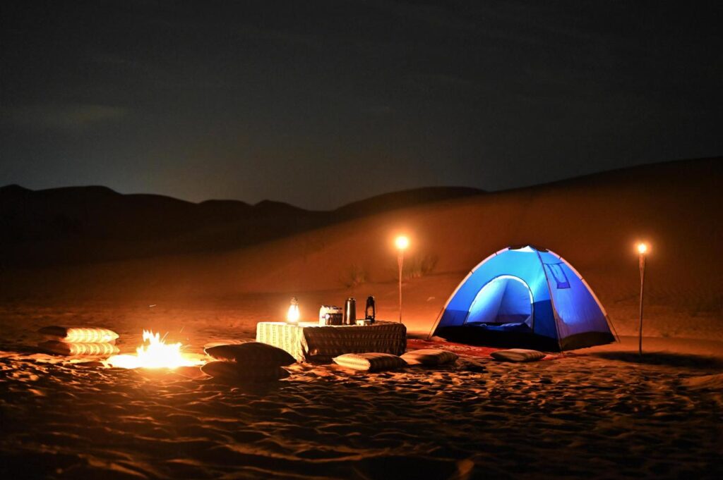 Overnight desert safari in Dubai with private tent camping, campfire, lanterns, and peaceful sand dunes at night
