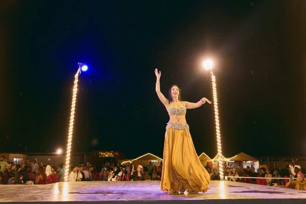 Belly dancer in a gold costume on a lit stage at night