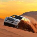 SUV driving through desert sand dunes