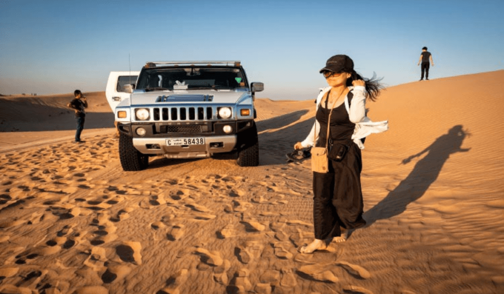 White Hummer on a desert dune with a guest standing beside it