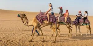 Tourists riding a line of camels across the desert