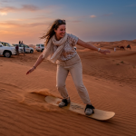 Woman sandboarding in desert sunset