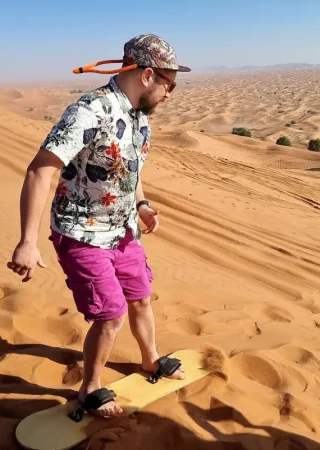 Tourist enjoying sandboarding on the golden dunes during a Dubai desert safari