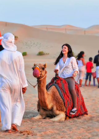 Guest enjoying a camel ride experience during an evening desert safari in Dubai