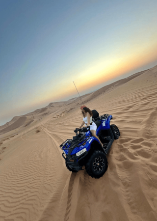 Tourists riding a quad bike in the Dubai desert during sunset